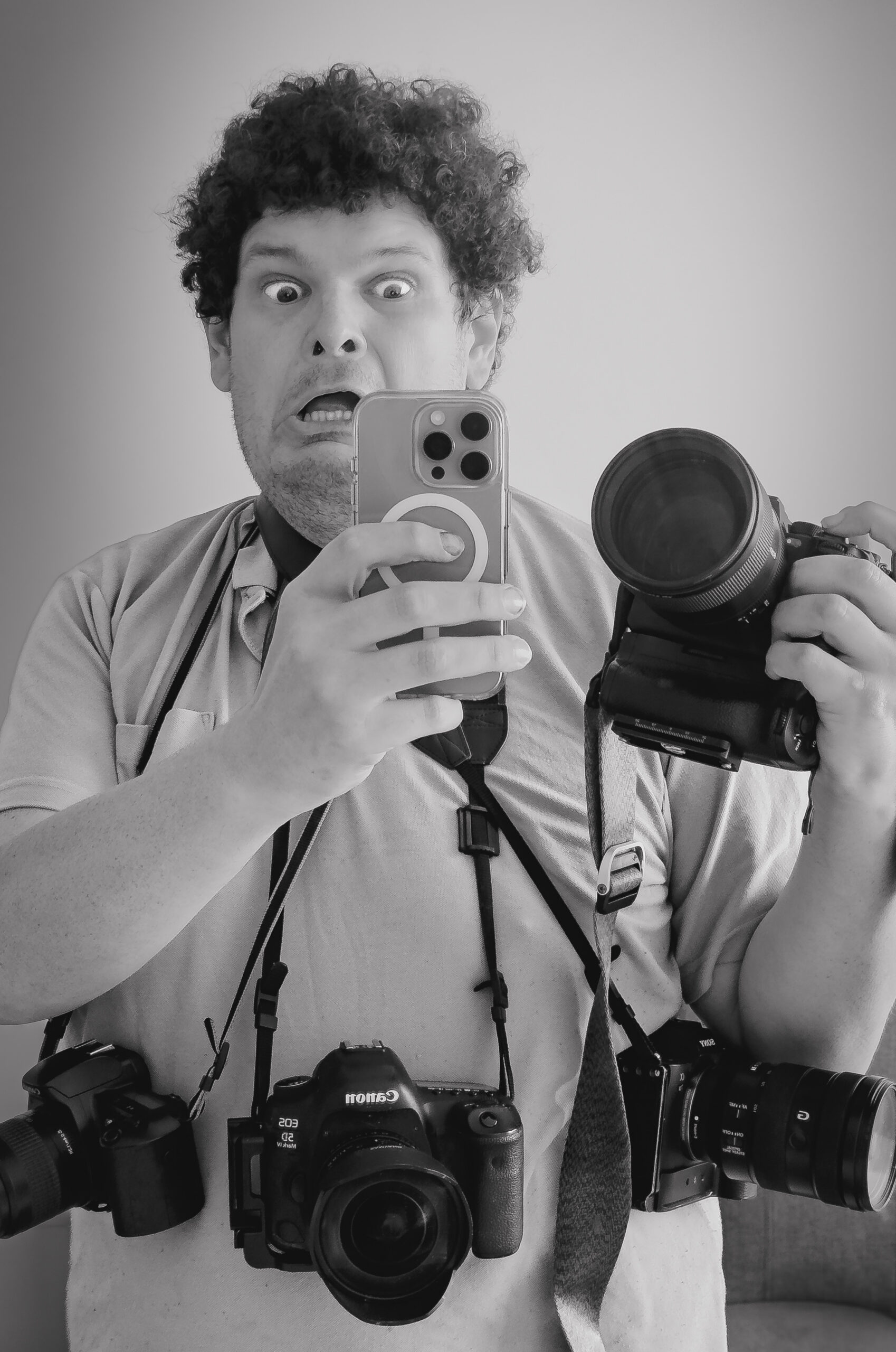 Ben is pictured taking a selfie in a mirror with his iPhone while holding 4 other cameras